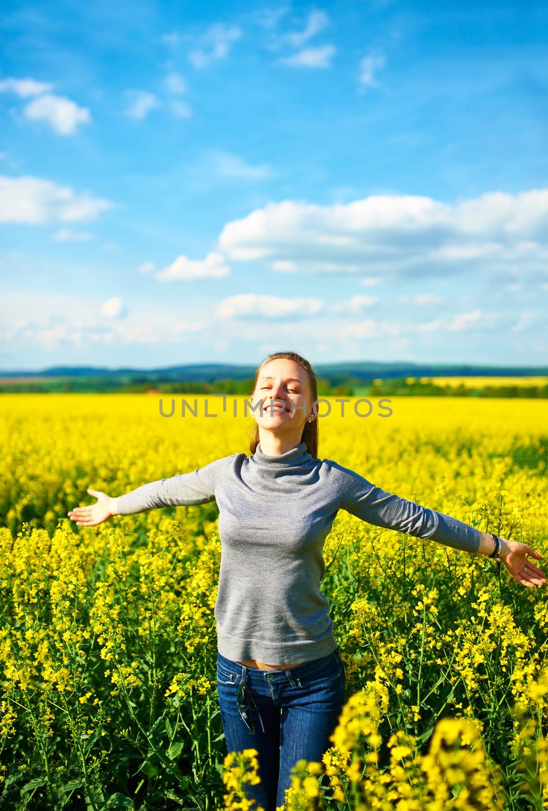 Girl with outstretched arms at colza field
