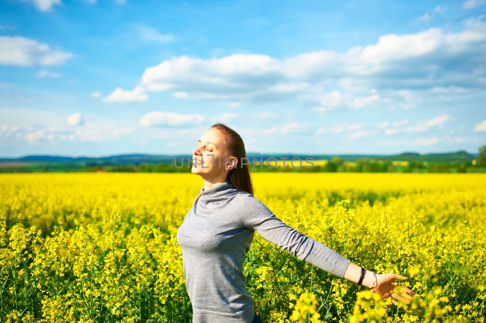 Girl with outstretched arms at colza field