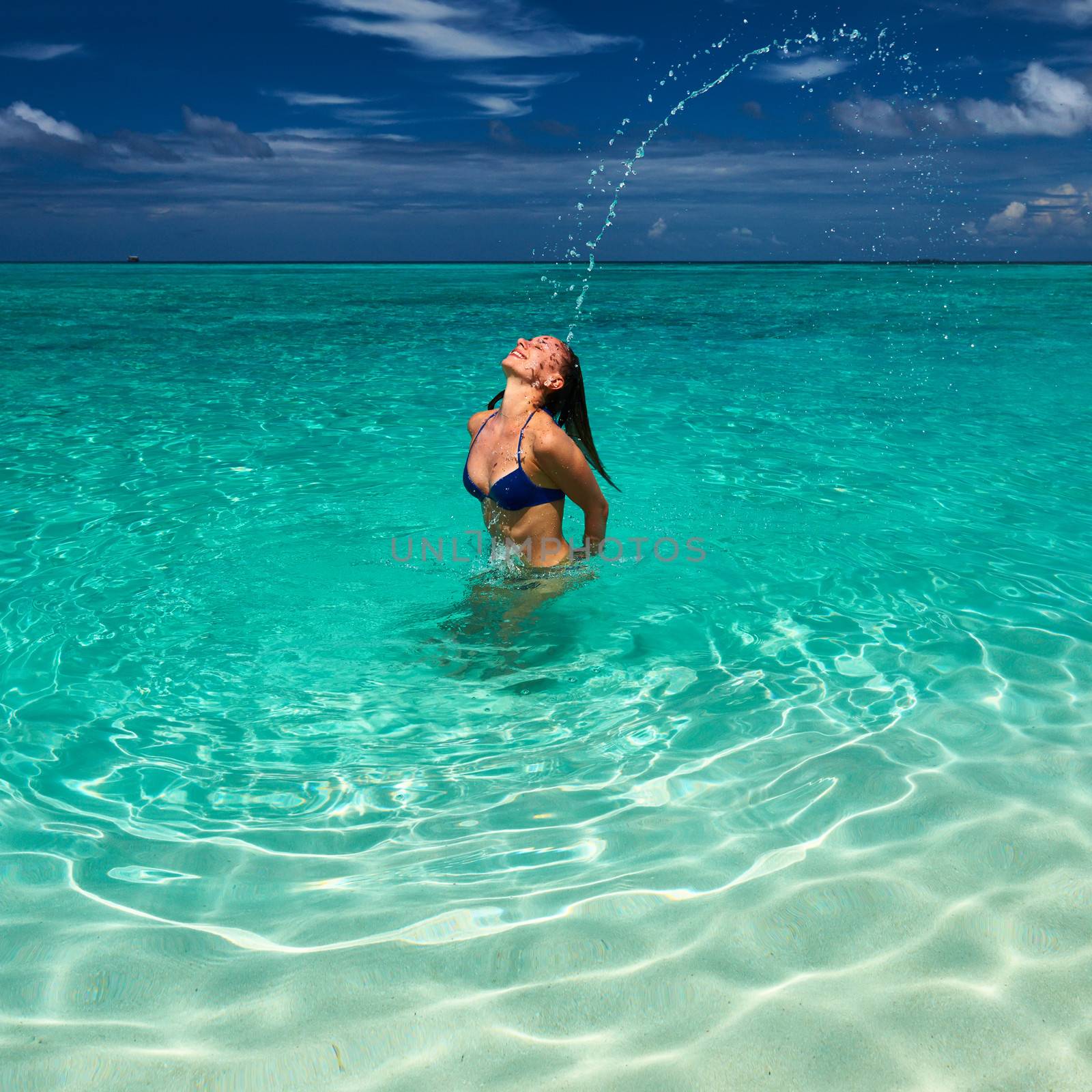 Woman splashing water with her hair in the ocean