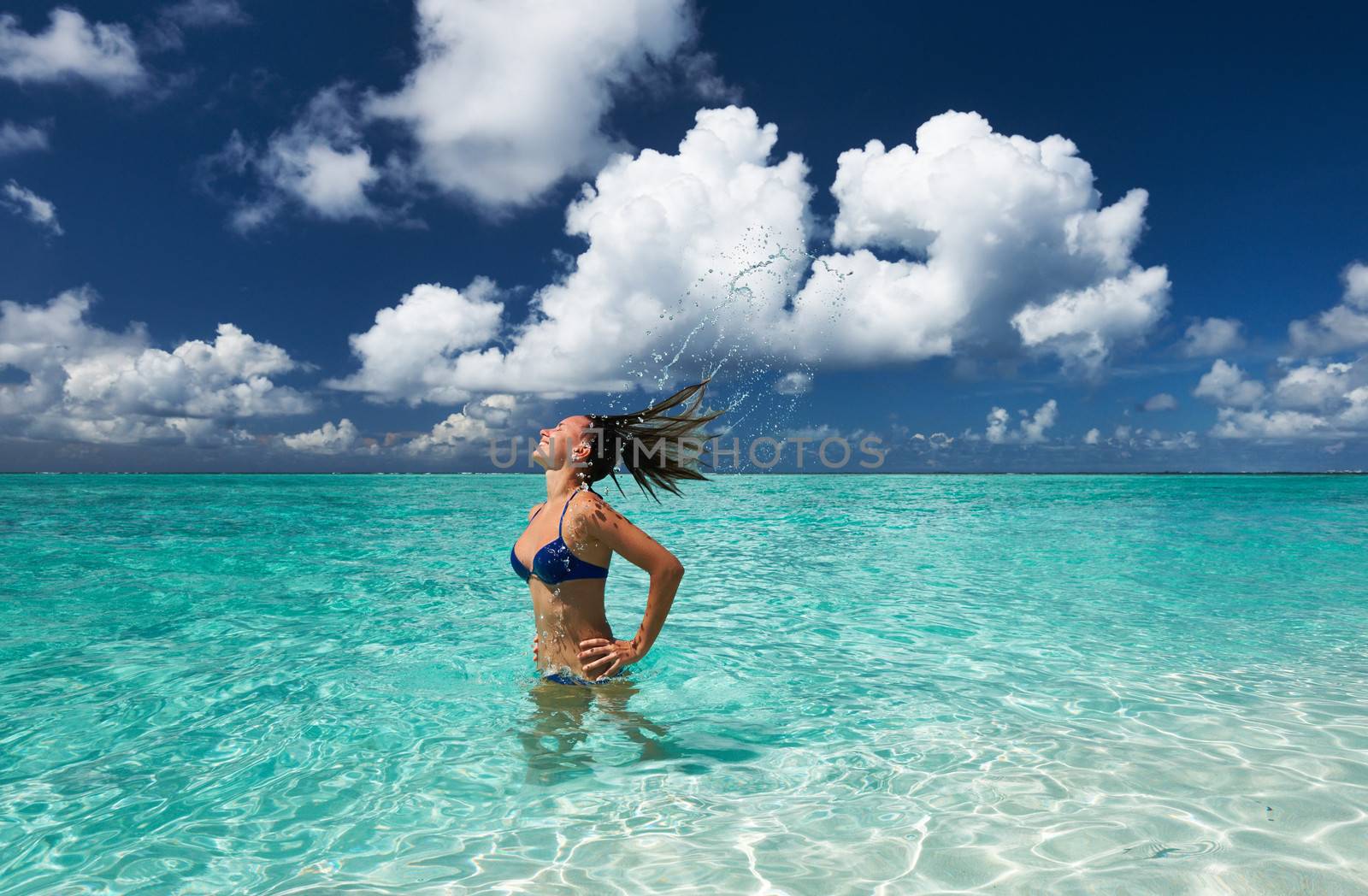 Woman splashing water with her hair in the ocean