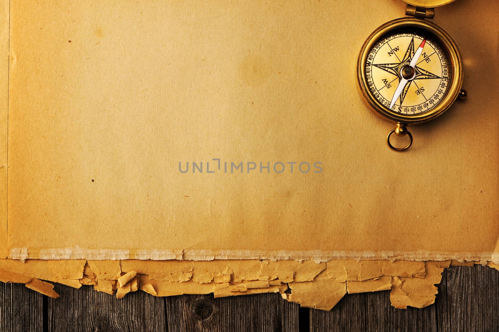 Antique brass compass over old paper background
