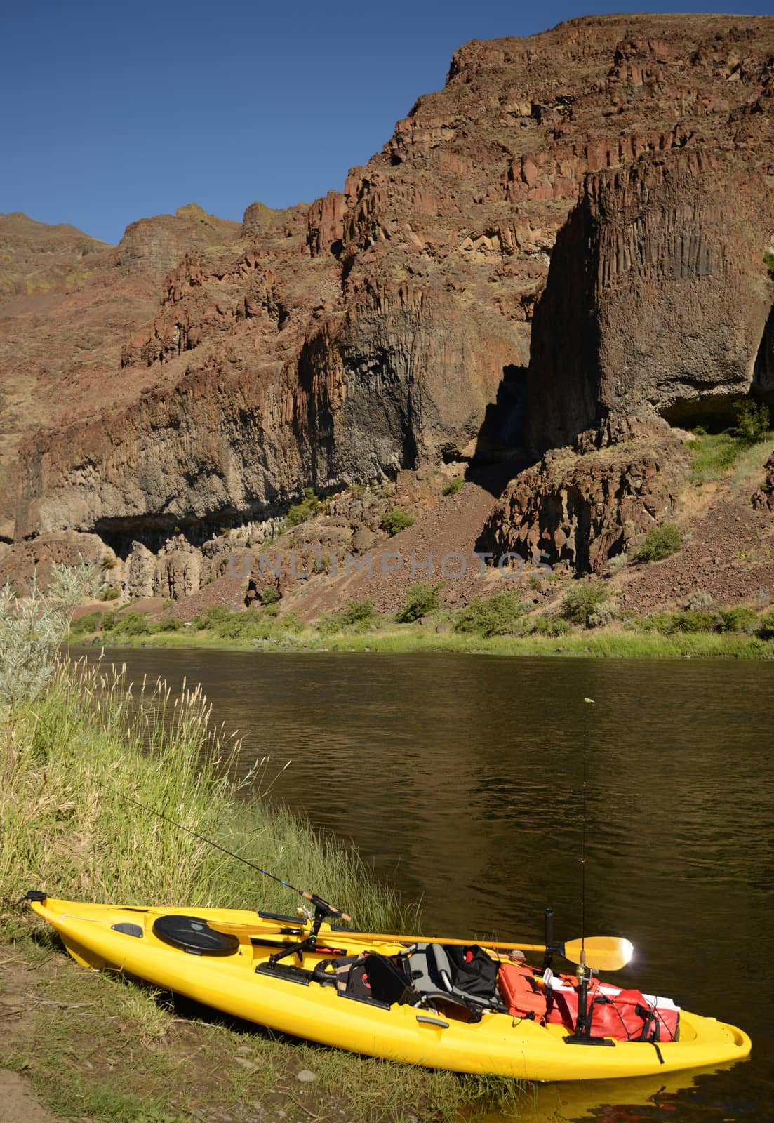 a kayak with nobody on a river in Oregon with mountains by ftlaudgirl