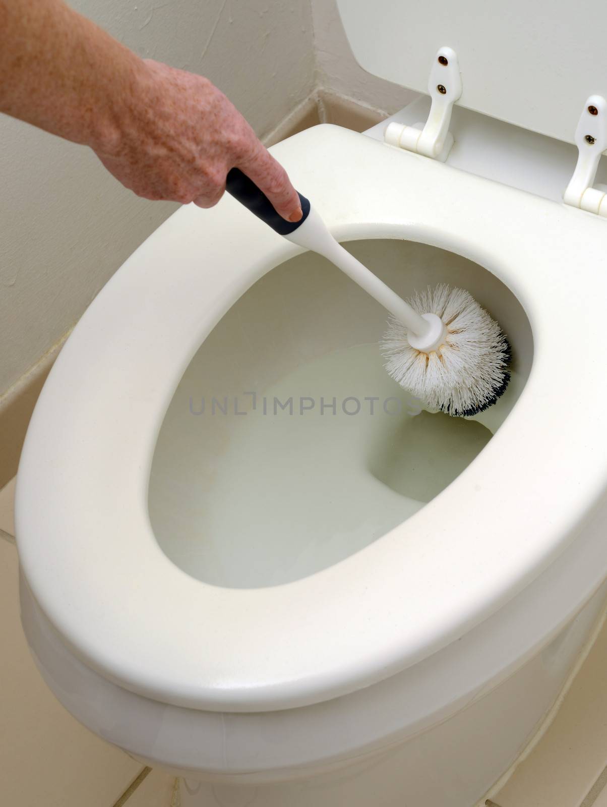 person scrubbing a white toilet with a scrub brush
