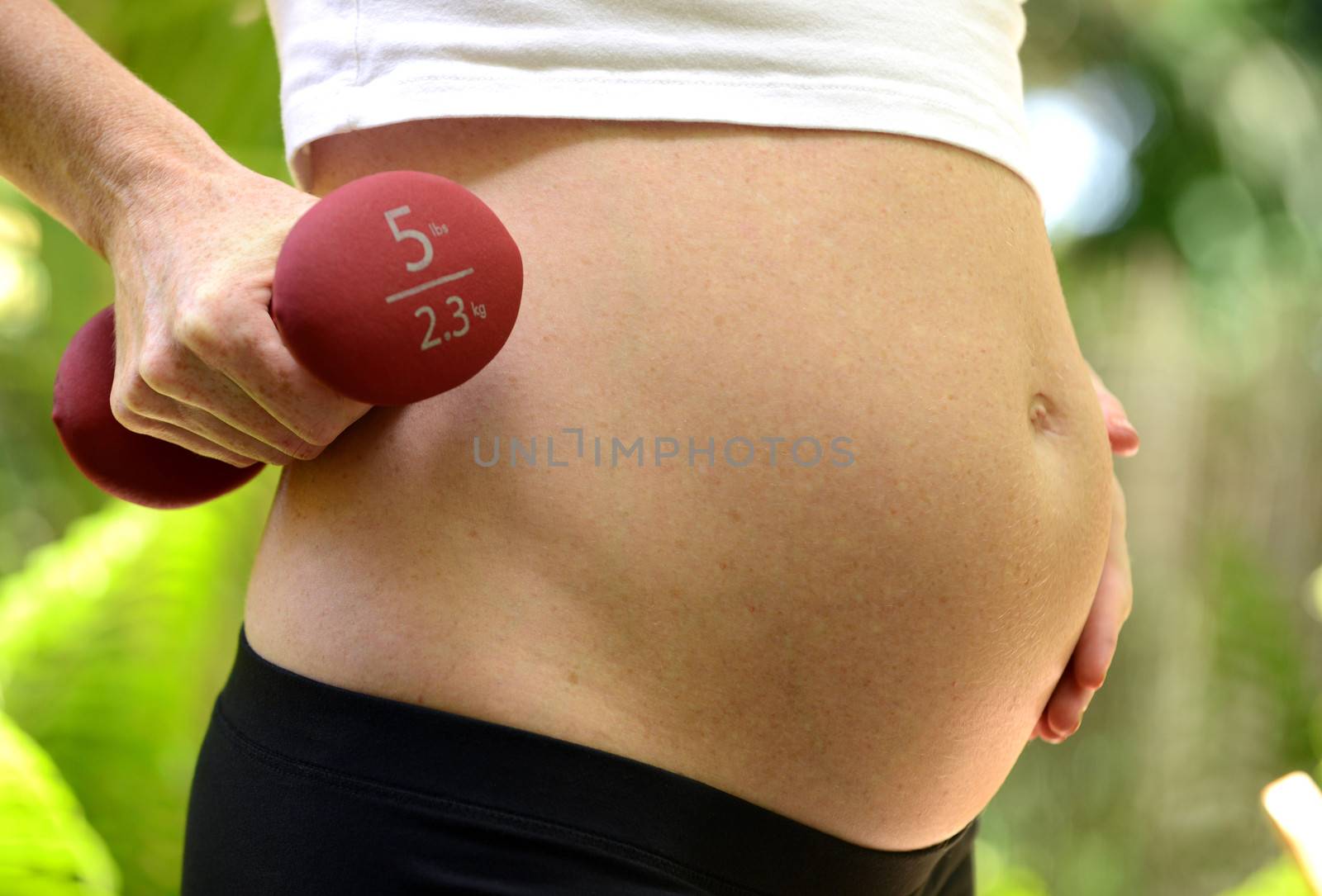 pregnant woman holding five pound dumbbell to workout during pregnancy