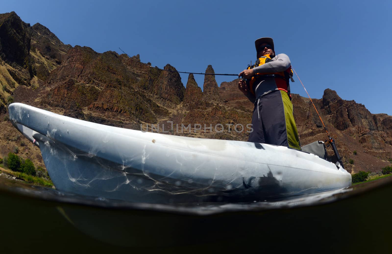 man fishing in kayak in beautiful landscape in Oregon with mountains and river