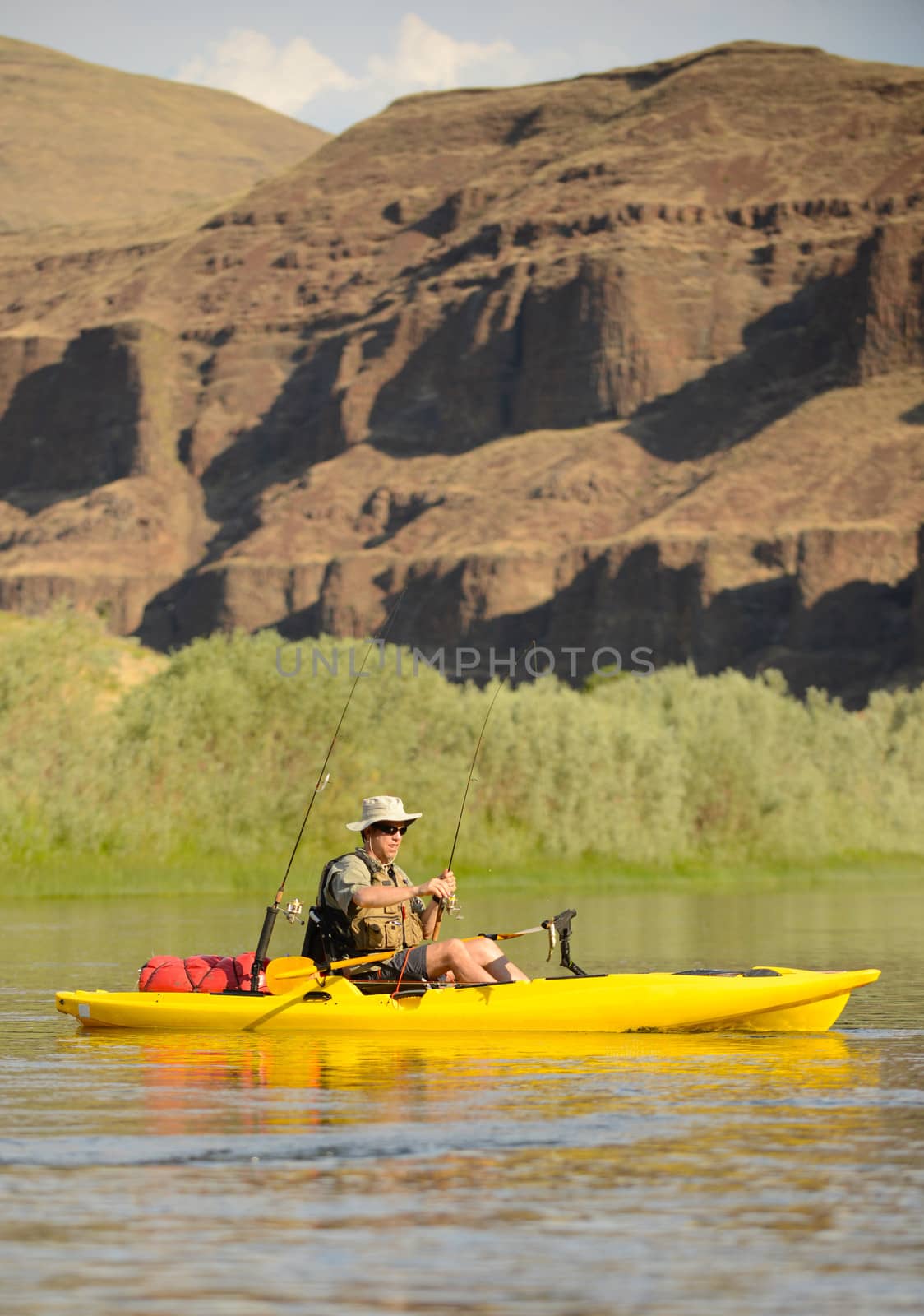 a solitude man fishing in a kayak on a river in the summer