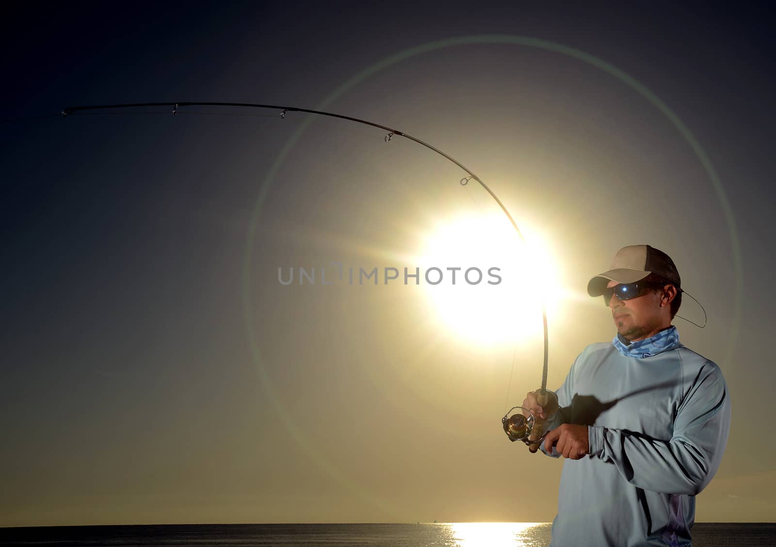 Man fishing with fishing rod and reel during sunrise