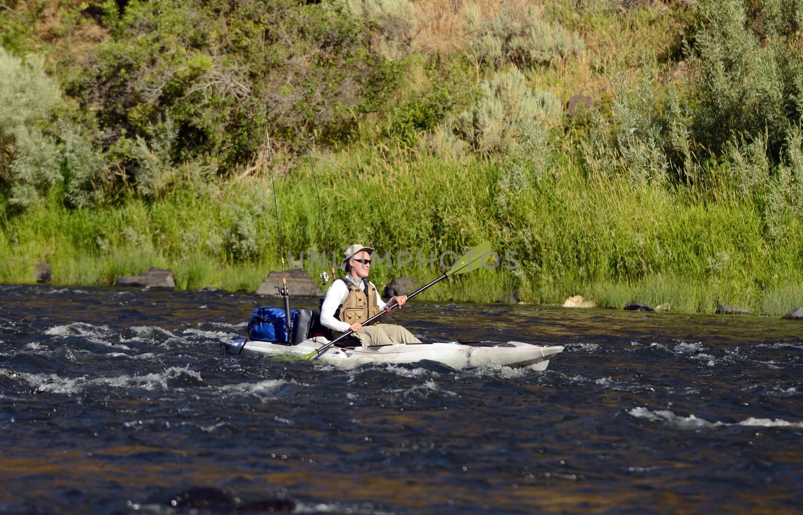 one man alone on a river fishing in a kayak on John Day River in Central Oregon