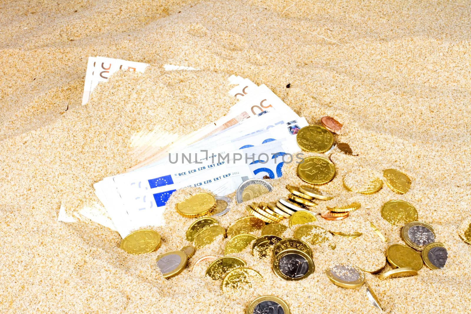 Euro notes and coins in the sand