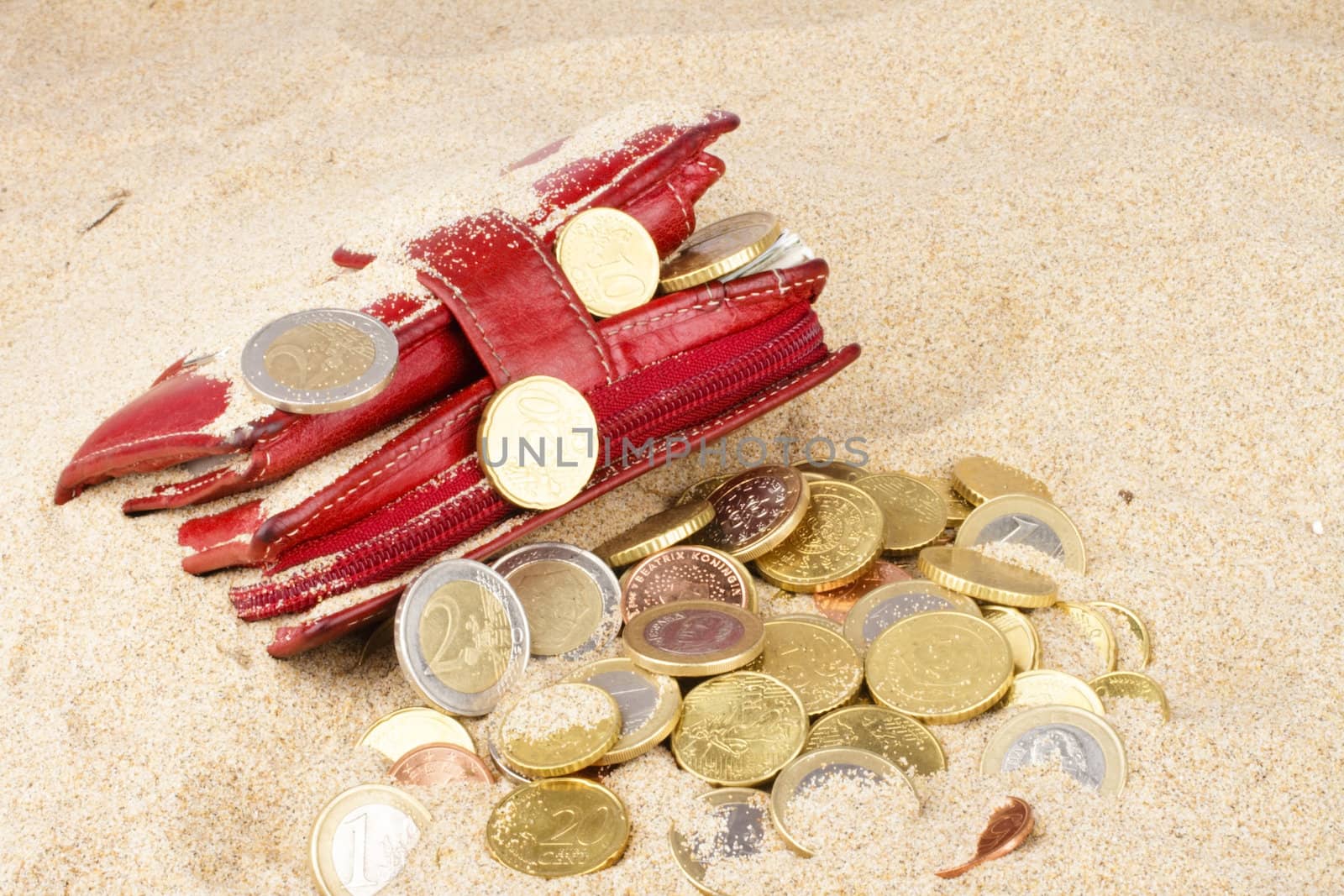 Red wallet with euro coins in the sand