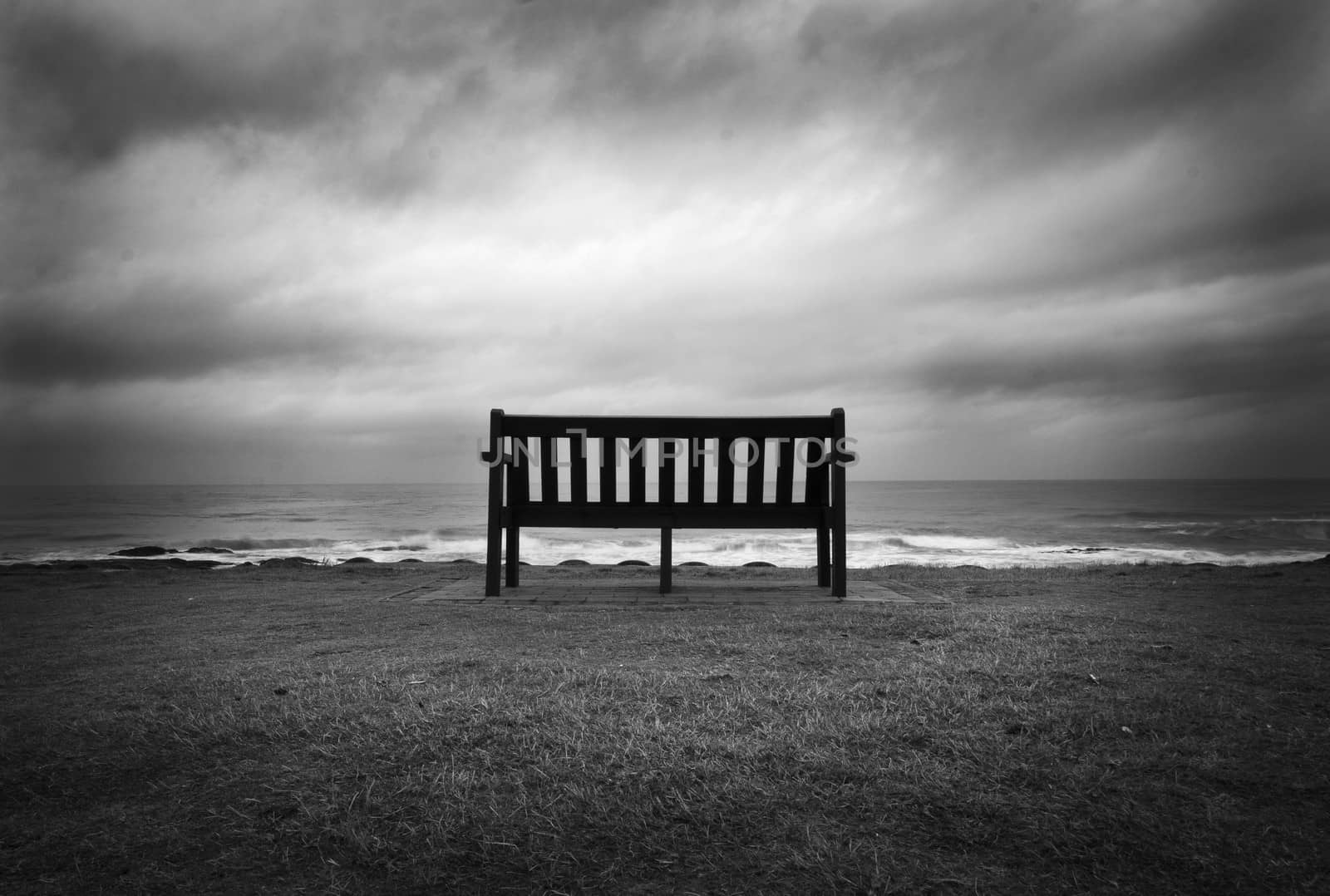 Lonely Bench facing the ocean and dramatic sky