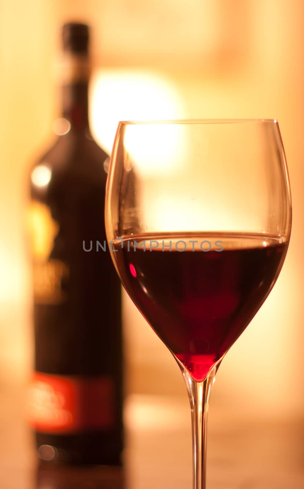 Glass of red win with a bottle in a evening restaurant setting