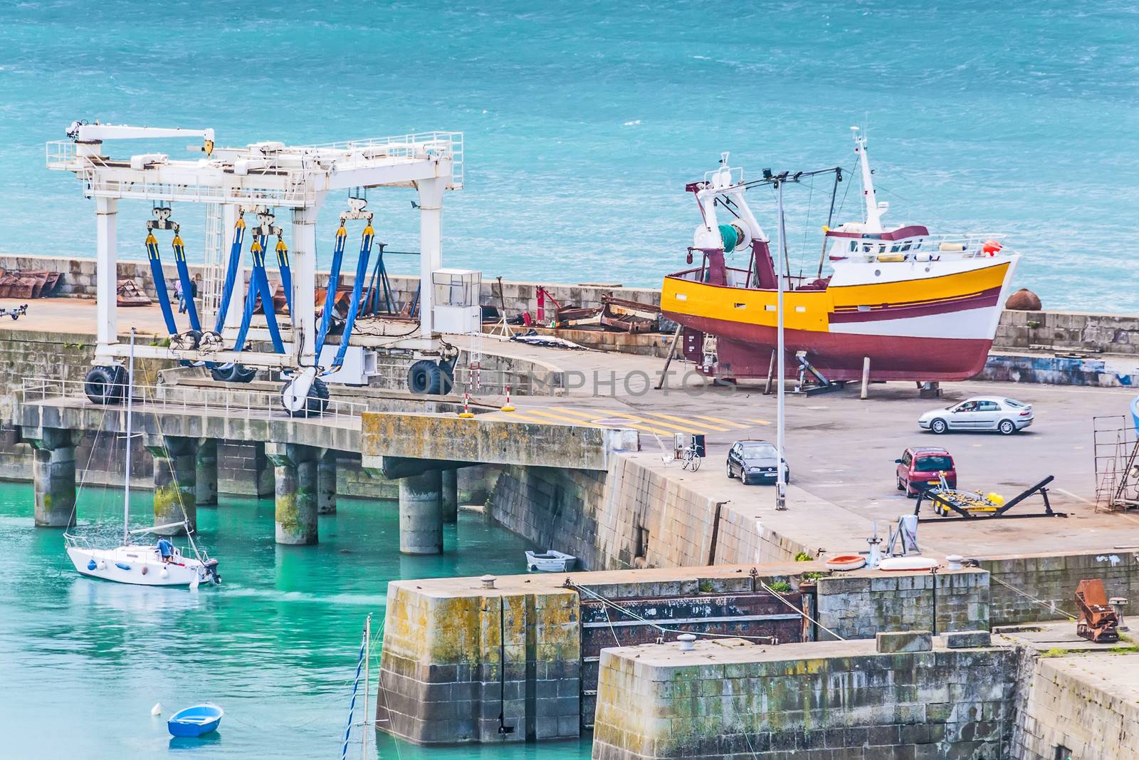 View of industrial port with ship, crane, wharf, cars and workers