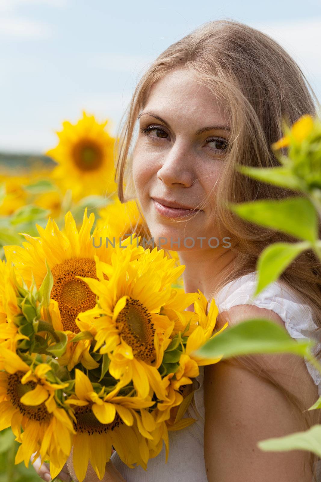 Beautiful long-haired young woman in the field with sunflowers