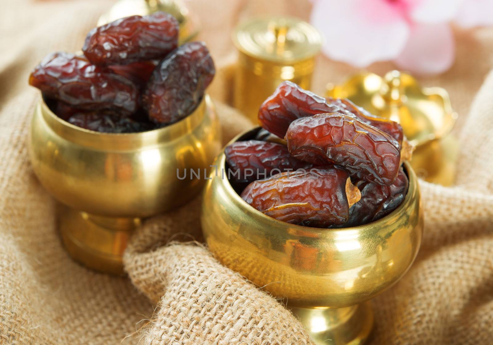 Dried date palm fruits or kurma, ramadan food which eaten in fasting month. Pile of fresh dried date fruits in golden metal bowl.