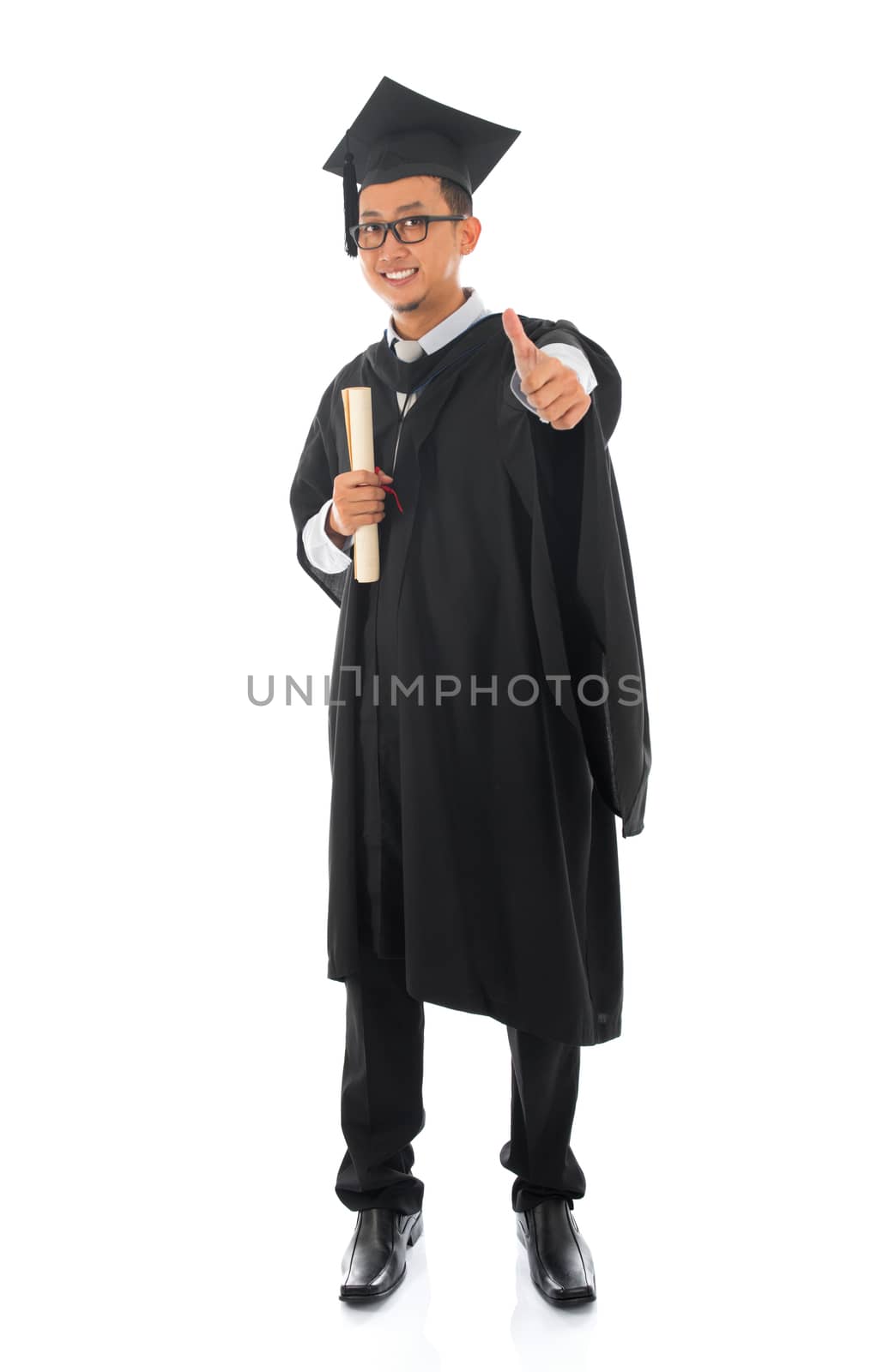 Full body Asian male university student in graduation gown thumb up isolated on white background