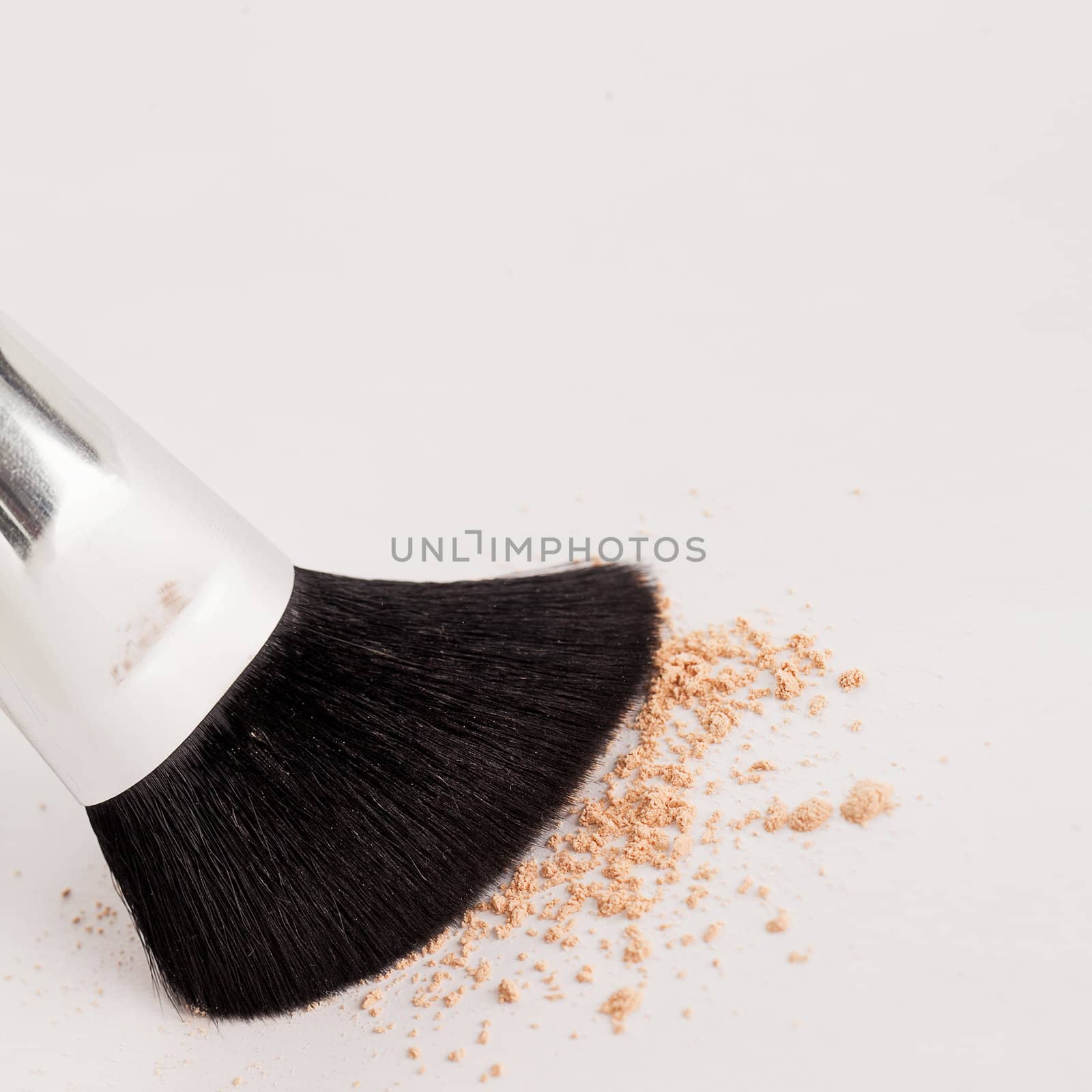 Makeup natural brush with beige powder on a white background