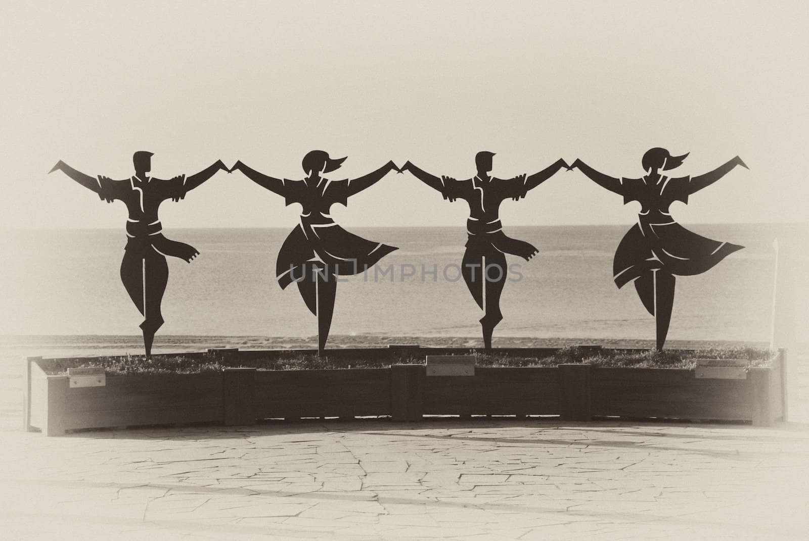 Statue of Catalonian dancers with the sea in background, in sepia