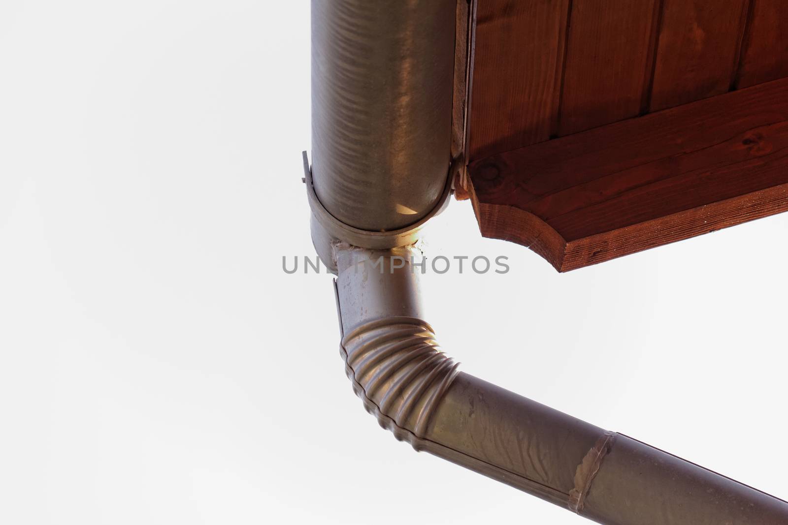 Corner of the house with gutters on a background of blue sky.