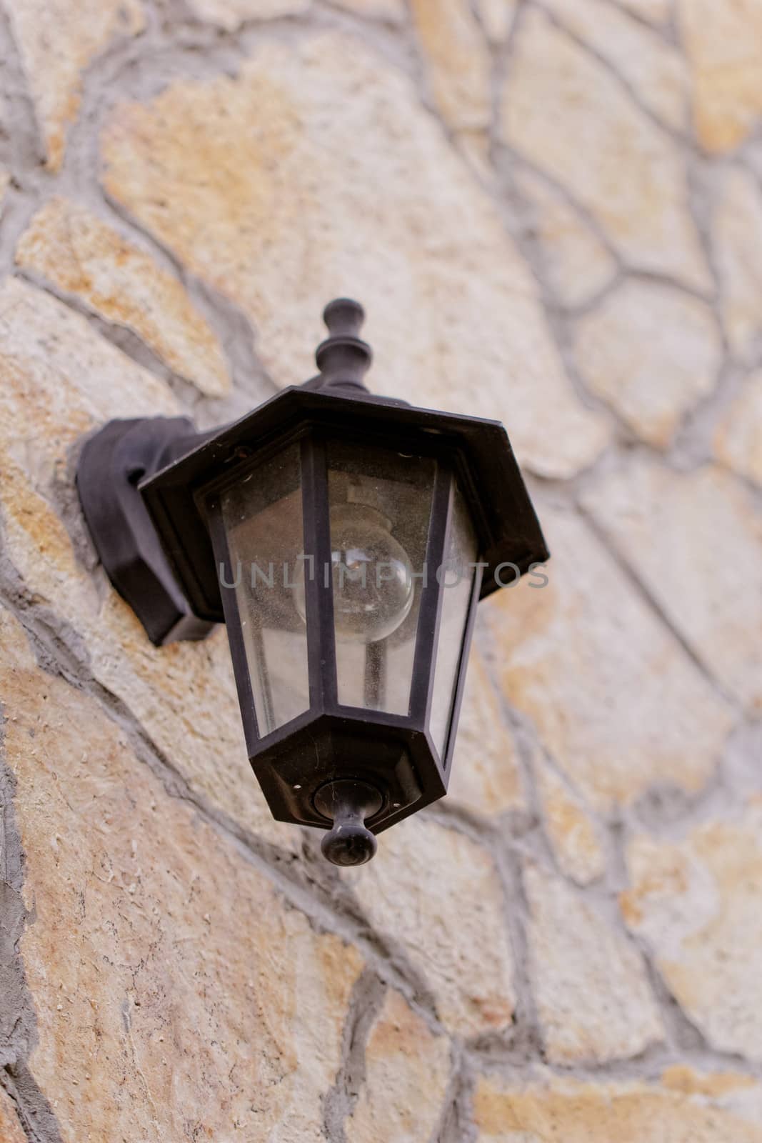 antique black lantern side by building (stone wall)