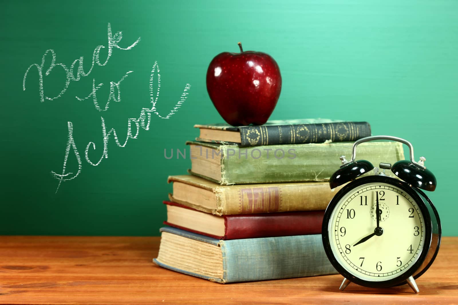 School Books, Apple and Clock on Desk at School by tobkatrina