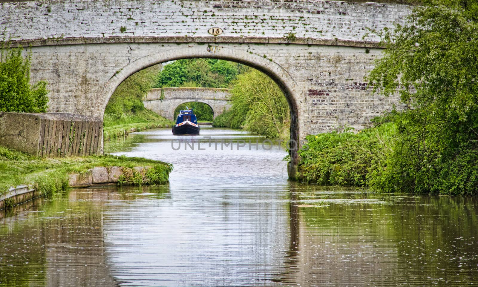 A narrowboat sailing on the Shropshire Union Canal between two bridges