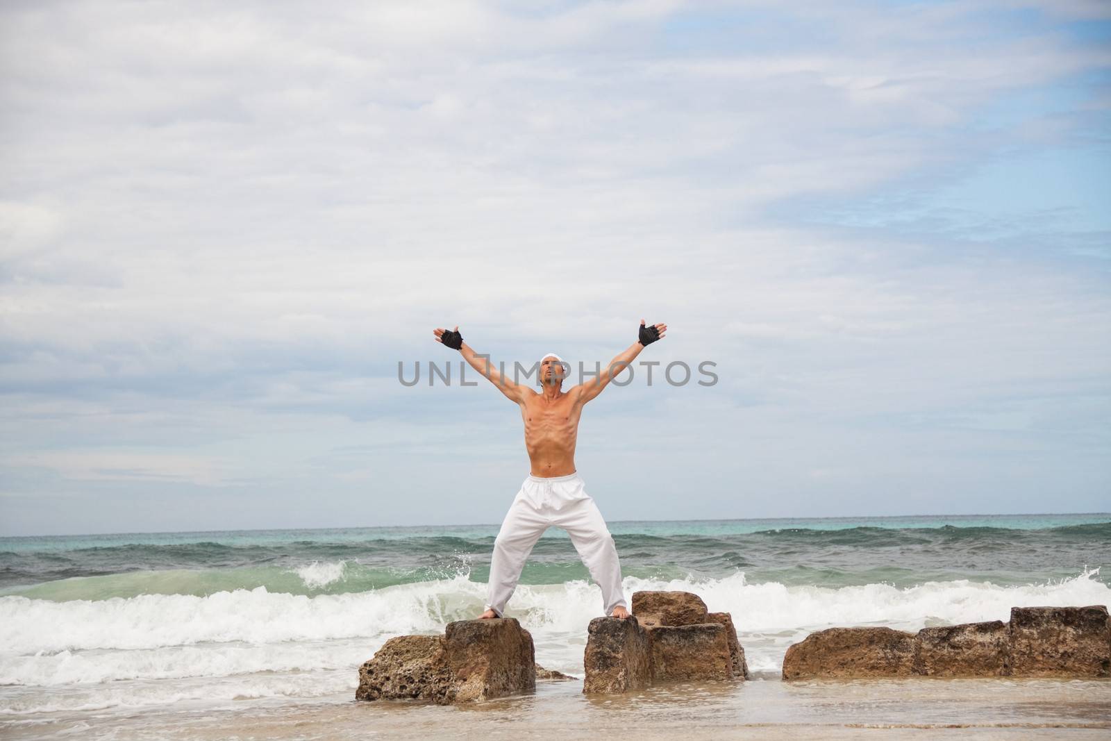 healthy man doing pilates yoga meditation on beach summer freedom