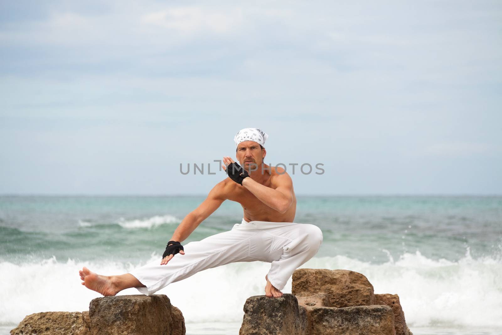 healthy man doing pilates yoga meditation on beach summer freedom