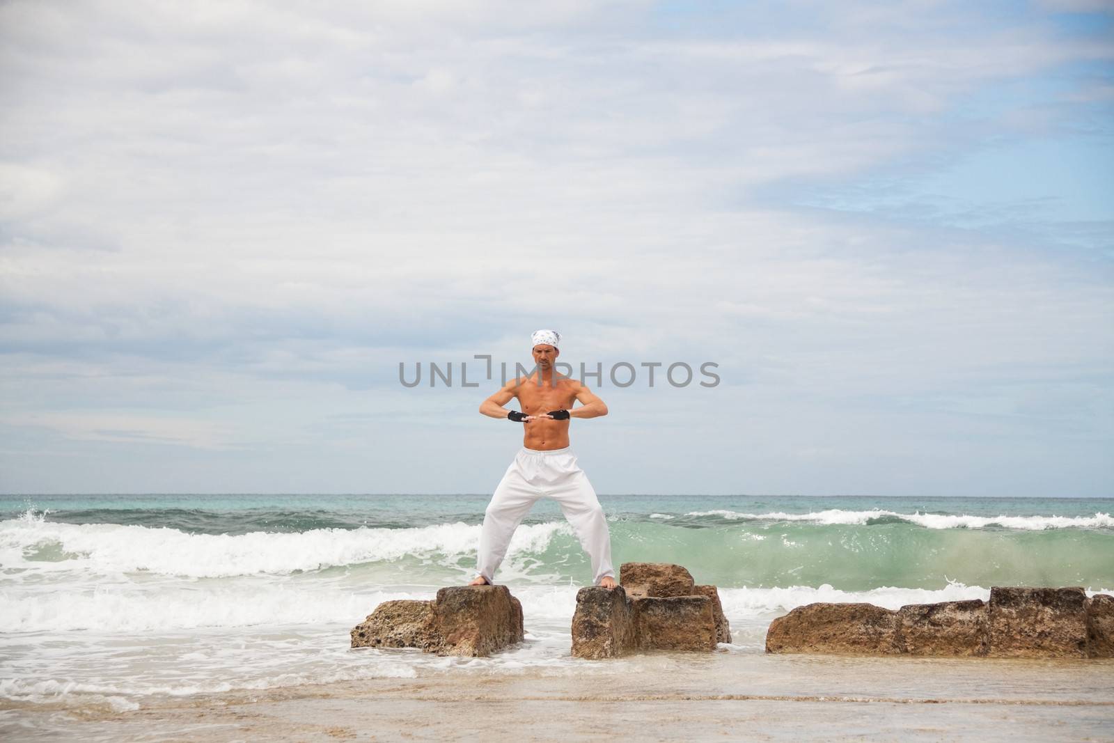 healthy man doing pilates yoga meditation on beach summer freedom