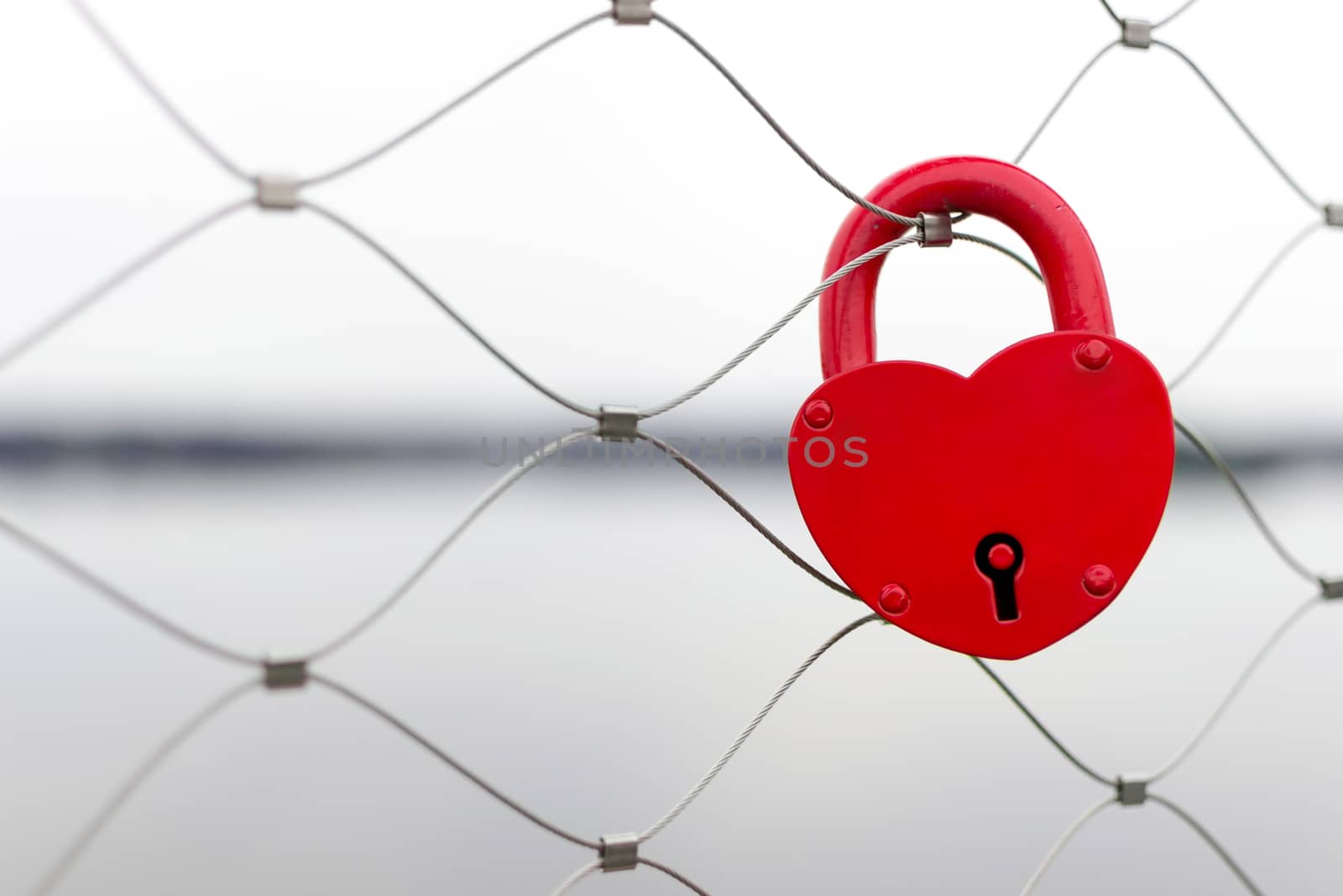 Red love padlock on bridge fence - wedding day tradition. Shallow depth of field