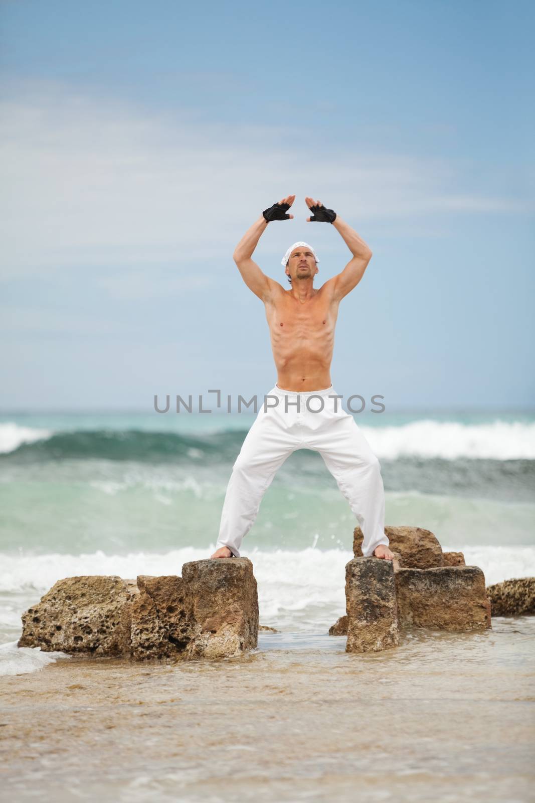 healthy man doing pilates yoga meditation on beach summer freedom
