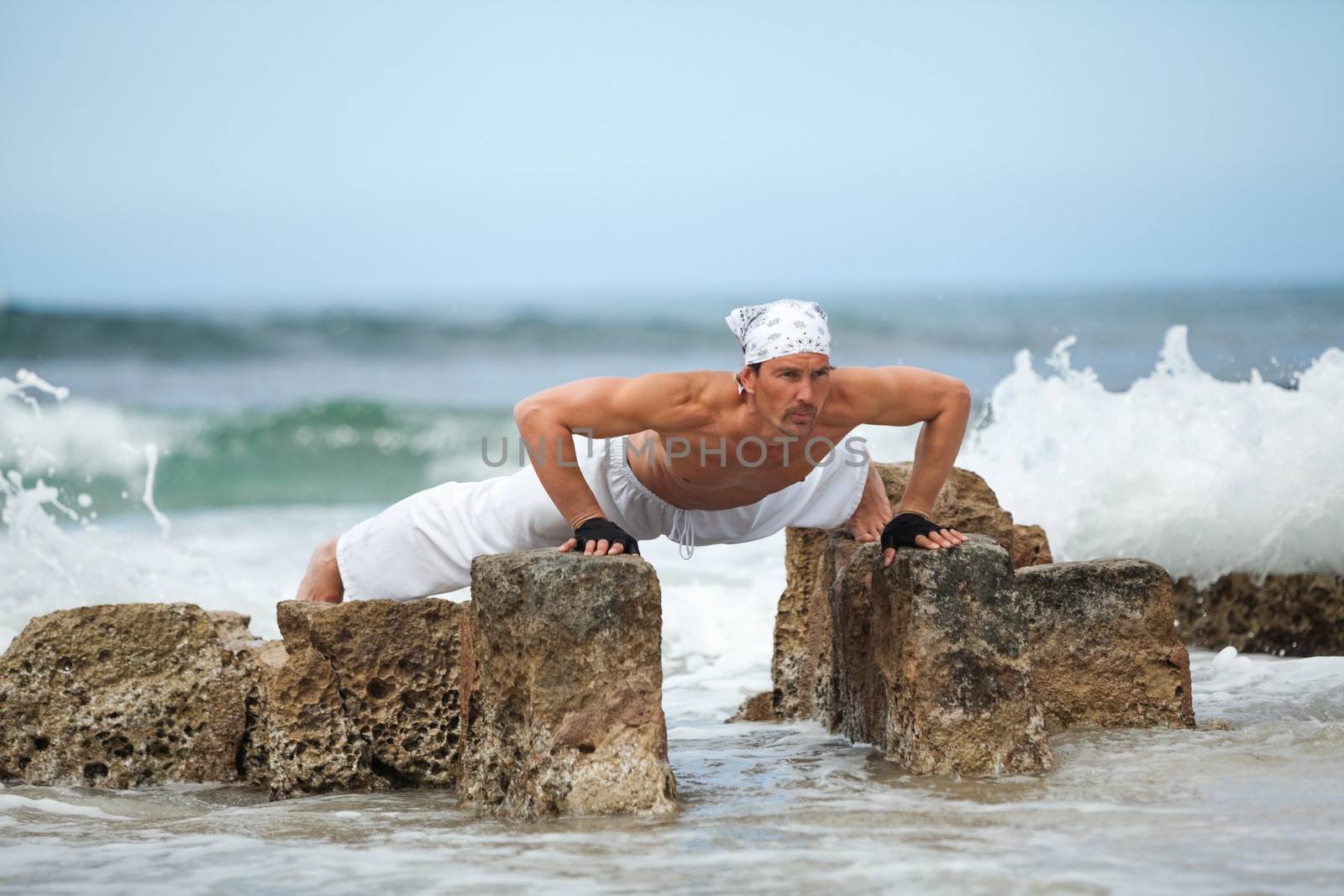 healthy man doing pilates yoga meditation on beach summer freedom