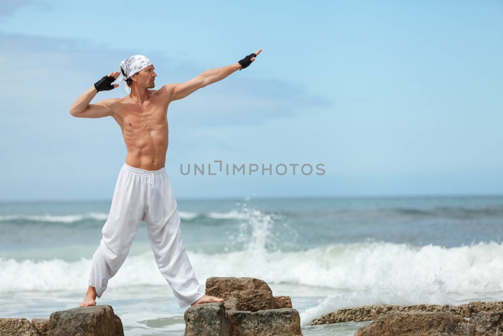 healthy man doing pilates yoga meditation on beach summer freedom