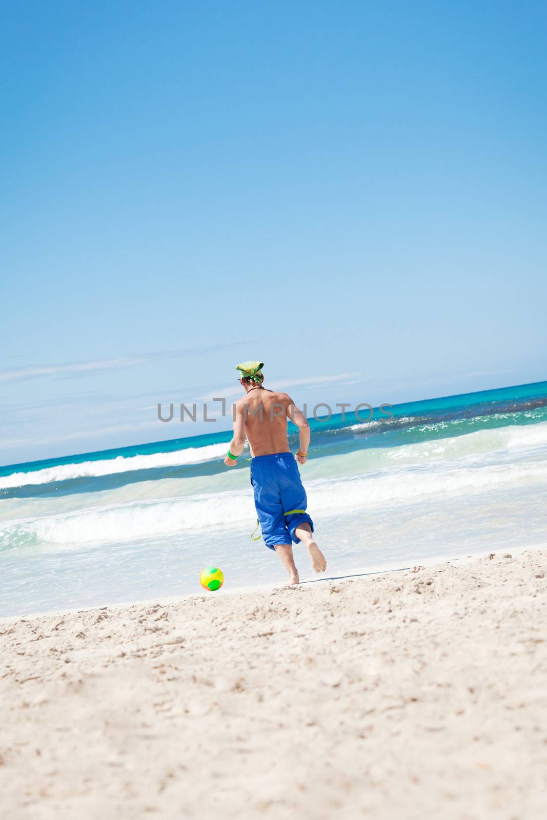 attractive young man playing volleyball on the beach summertime 