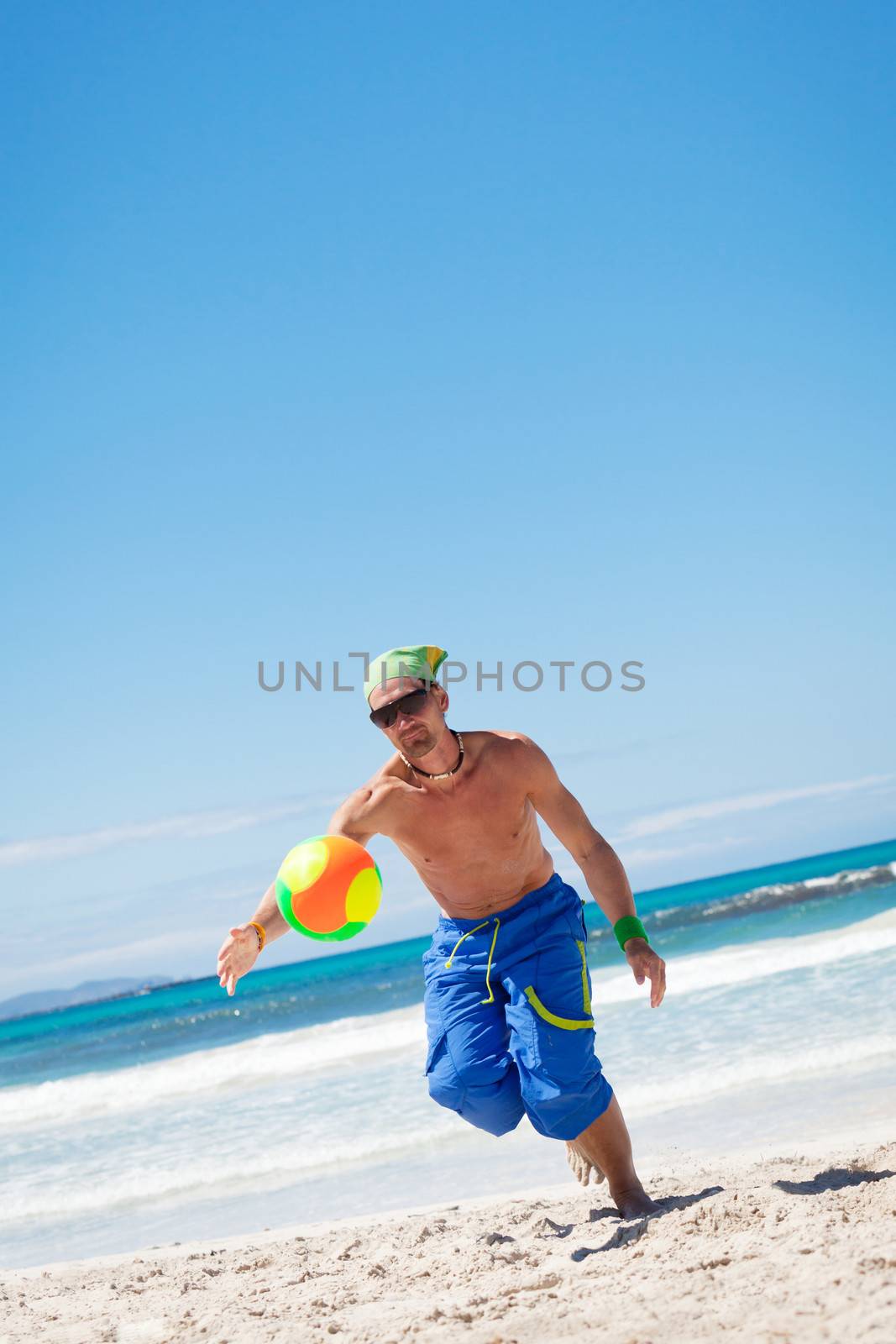attractive young man playing volleyball on the beach summertime 
