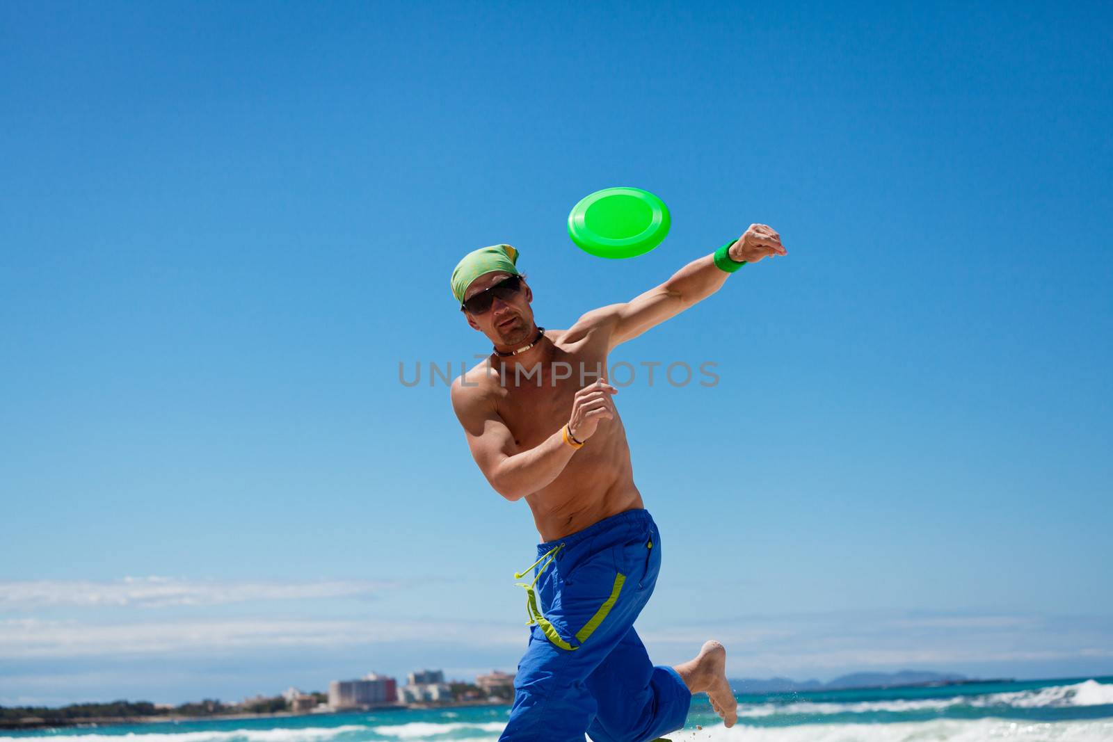 attractive man playing frisby on beach in summer sport fitness jump