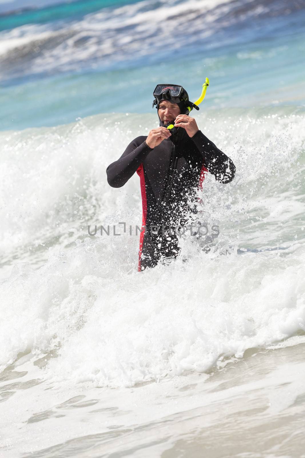 male diver with diving suit snorkel mask fins on the beach in Summer
