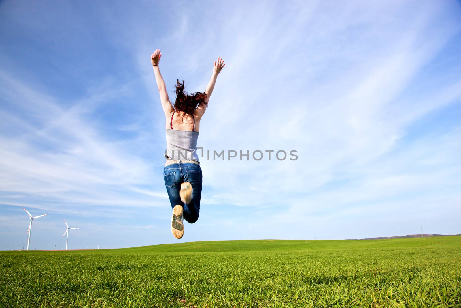 Young beautiful woman jumping for joy by photocreo