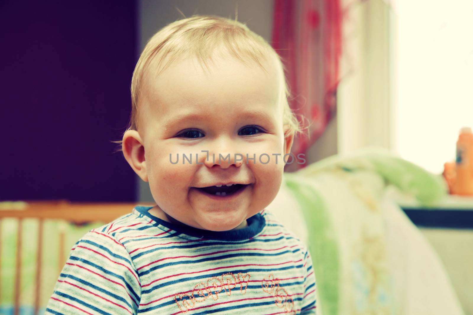 Happy kid laughing looking at the camera. Inside home portrait