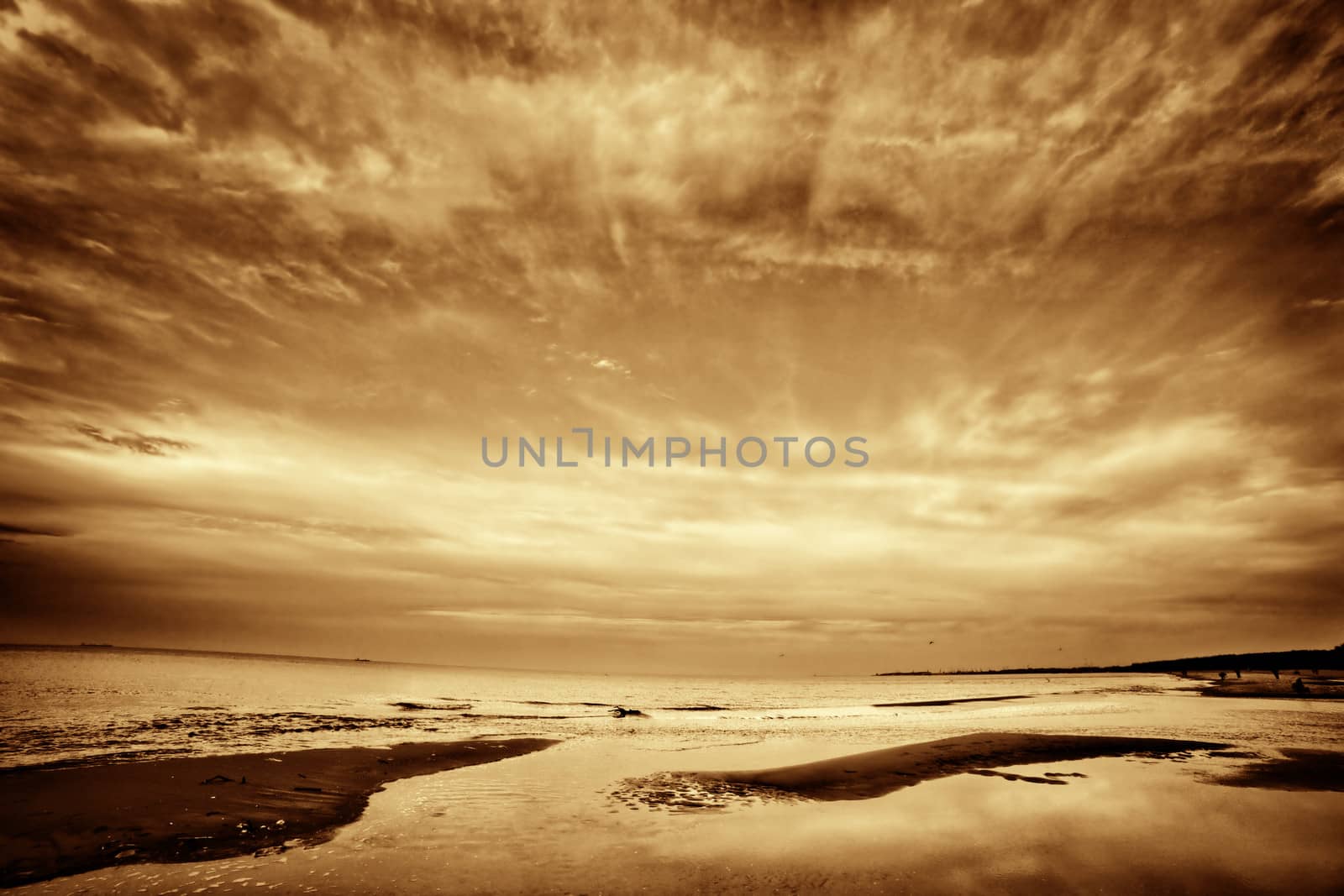 Fine art picture of sea, ocean at sunset. Dramatic sky, golden tint