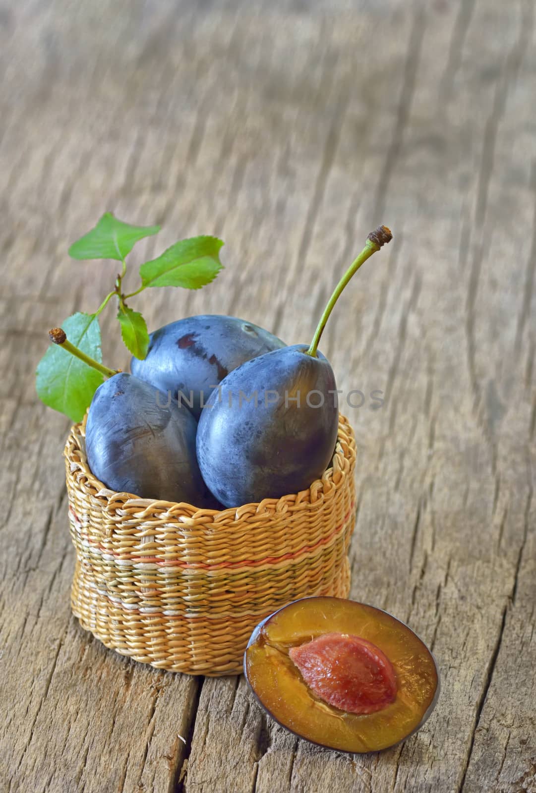 basket with plums on wooden background