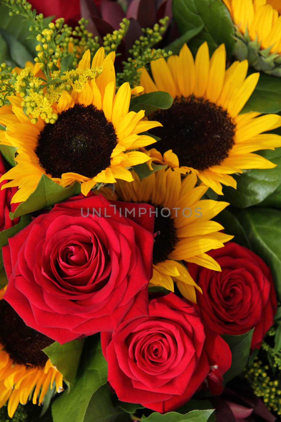 Red roses and sunflowers in a floral arrangement by studioportosabbia