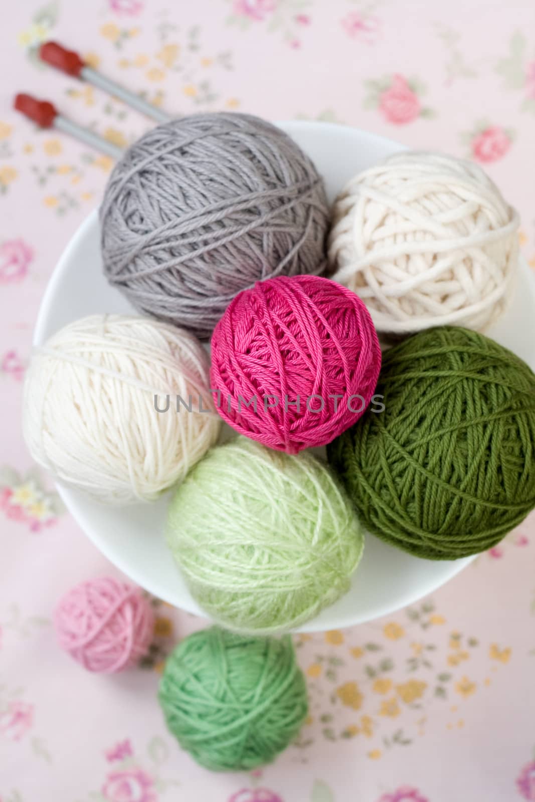 A lot of bright balls of knitting on the background of a pink flower