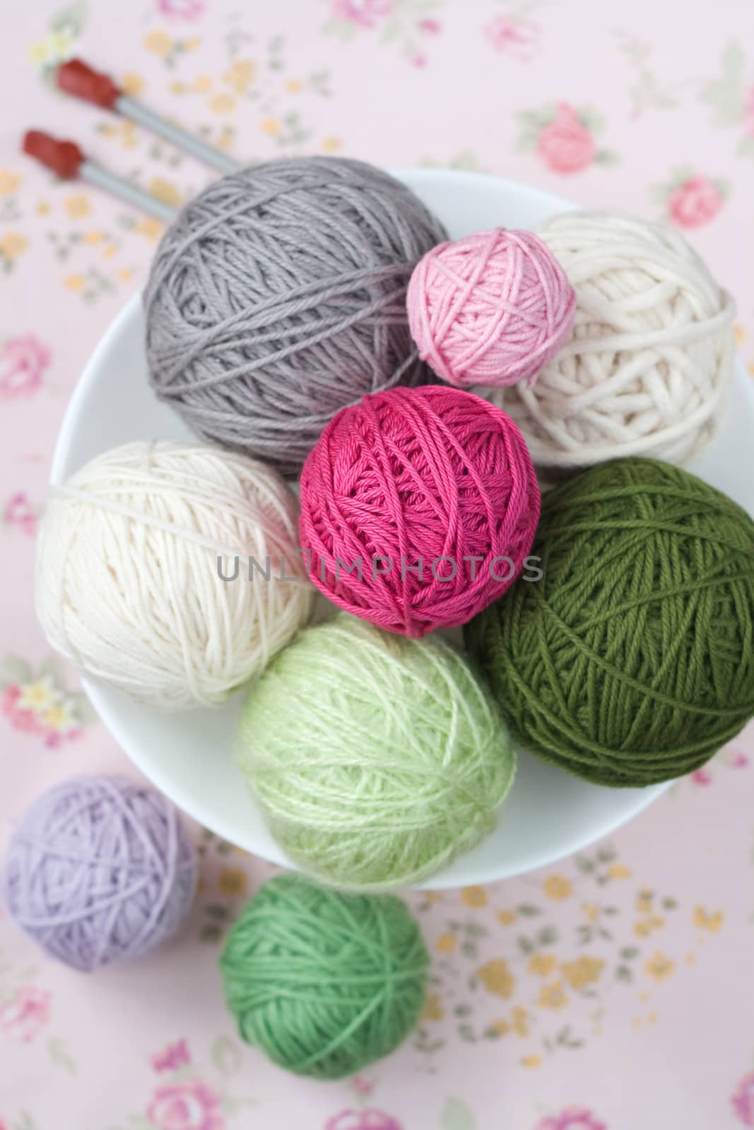 A lot of bright balls of knitting on the background of a pink flower
