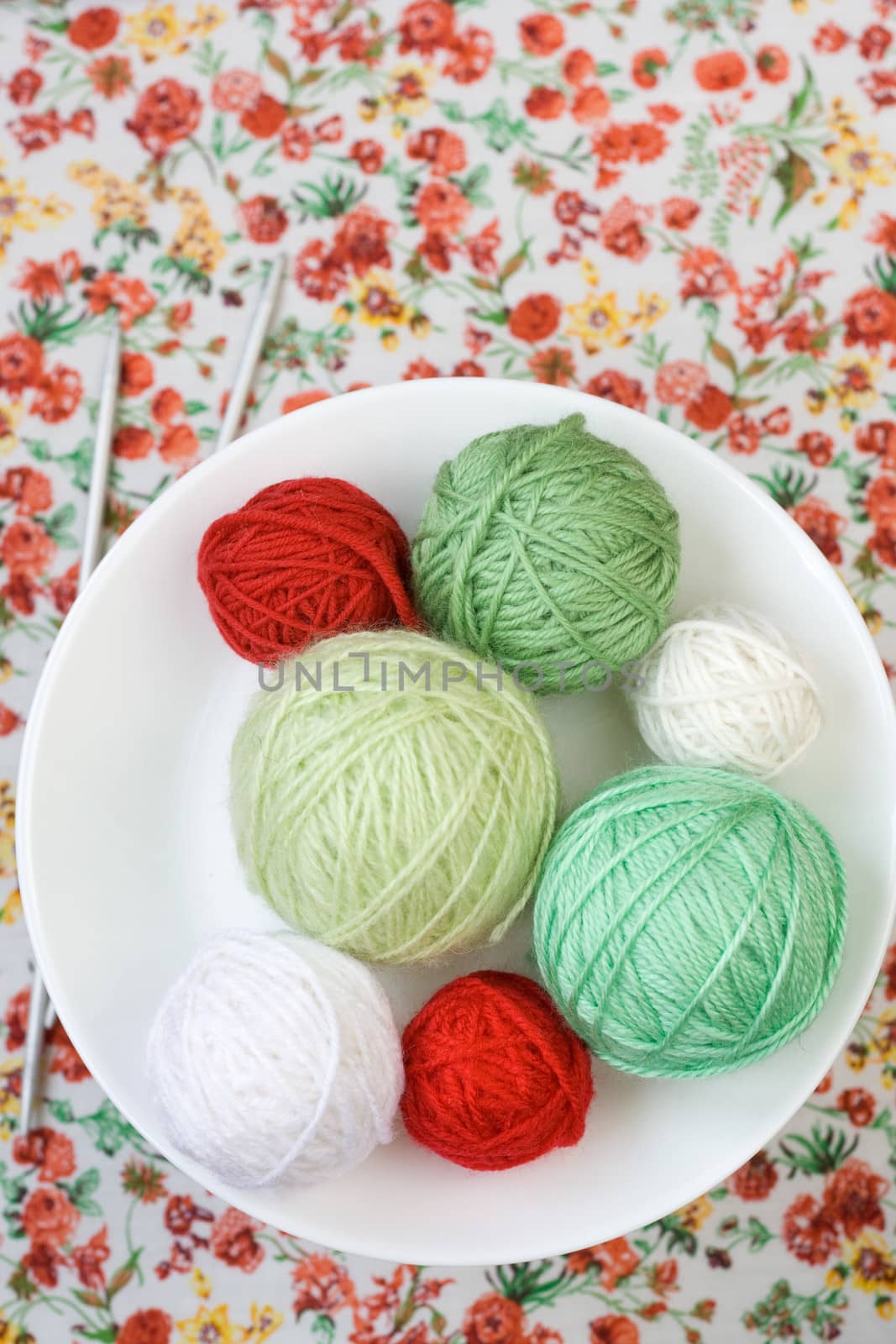 A lot of bright balls of knitting on the background of a red flower