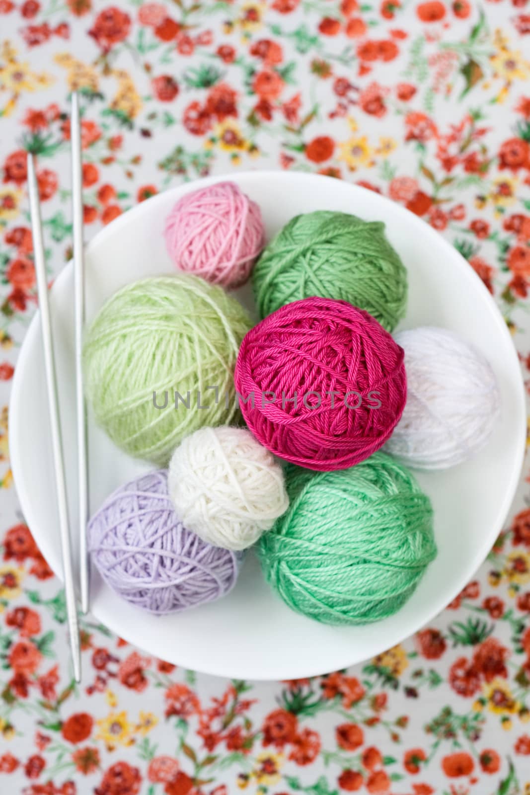 A lot of bright balls of knitting on the background of a red flower