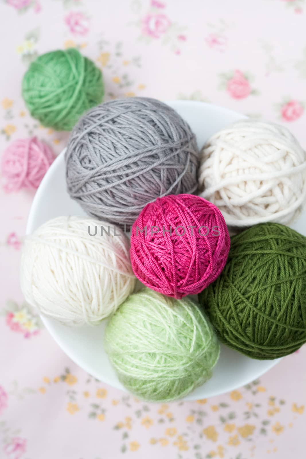 A lot of bright balls of knitting on the background of a pink flower