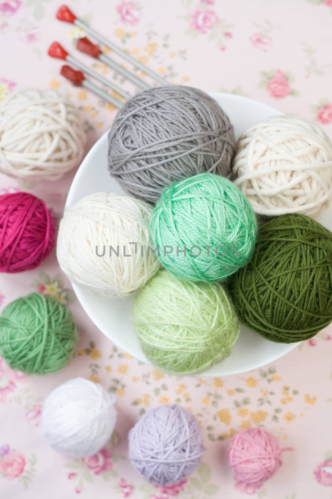 A lot of bright balls of knitting on the background of a pink flower