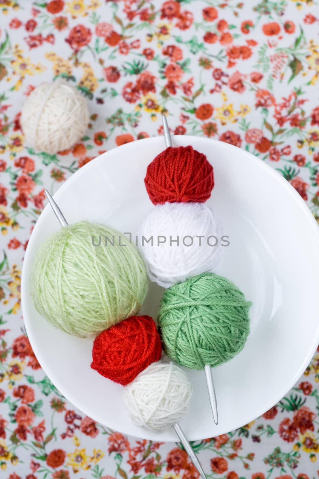 A lot of bright balls of knitting on the background of a red flower