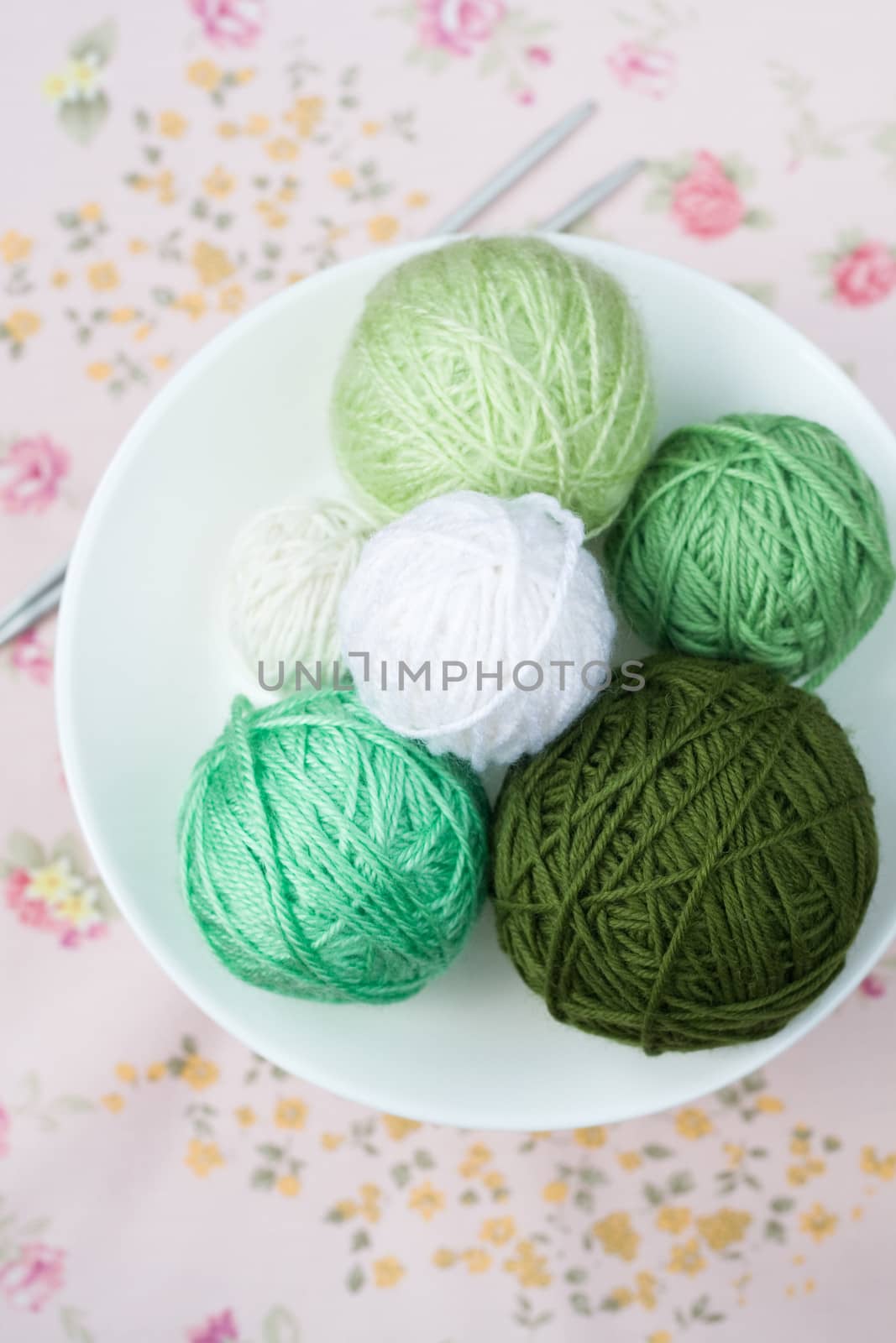A lot of bright balls of knitting on the background of a pink flower